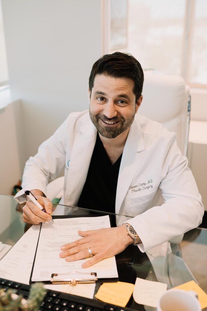 Dr. Steven Camp working on paperwork and smiling at camera